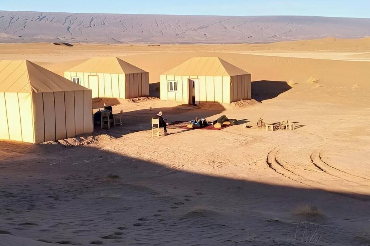 Paisaje desértico con varias tiendas de campaña y cielo despejado.