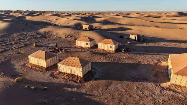 A desert landscape with several small, rectangular buildings with flat roofs. - starlitdesertcamp (Foum Zguid)