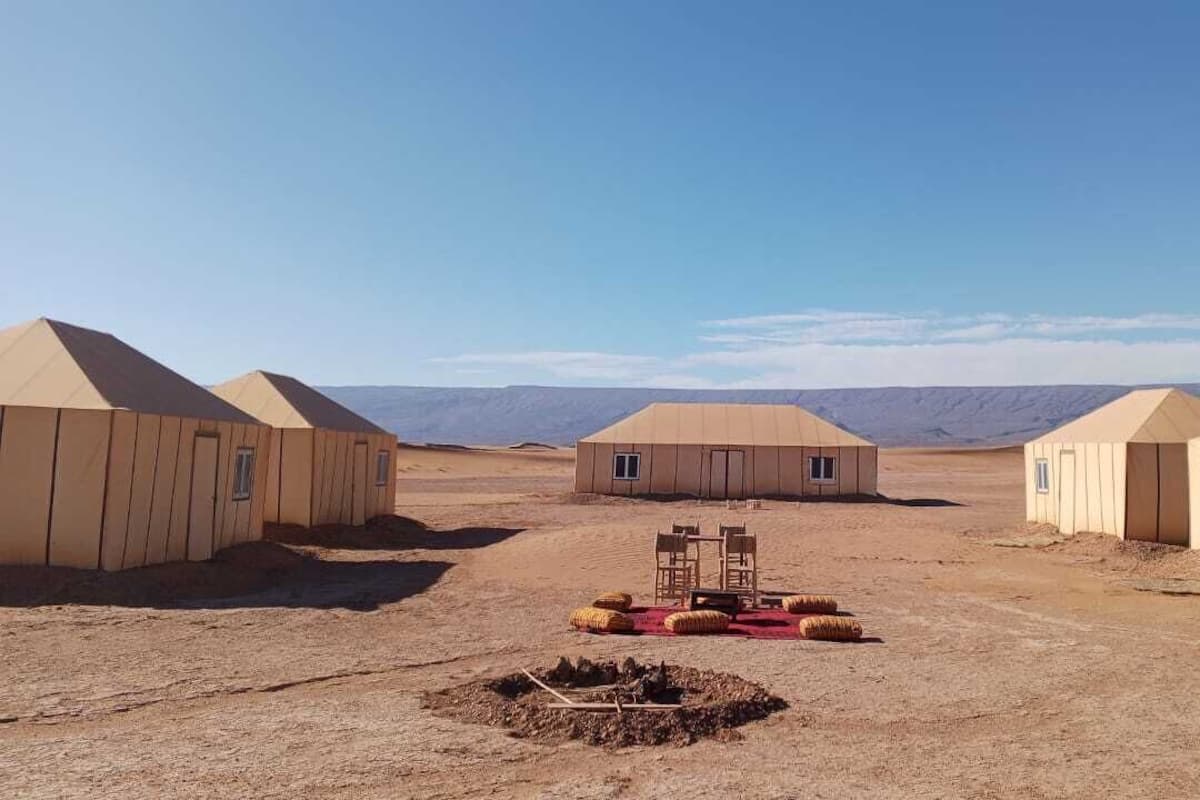 Paisaje desértico con cuatro tiendas de campaña beige alineadas.
