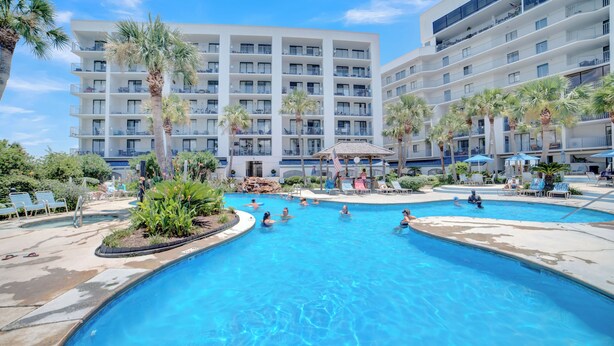 Un hotel con numerosi balconi, una piscina e palme.