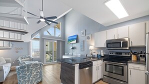 Een moderne keuken met een centraal eiland, roestvrijstalen apparatuur en een eetgedeelte met uitzicht.