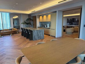 A modern kitchen with built-in appliances, a dining area with a marble island, and a living space with a sofa and a plant. - Luxury 2BR | Miami Water View & Skyline (Miami)