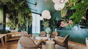 Une pièce meublée de mobilier en osier, agrémentée de plantes suspendues et dotée d’un mur végétal.