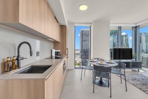 Een moderne keuken met een spoelbak, kasten en een eethoek met een tafel en stoelen.