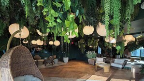 Une pièce décorée de plantes suspendues, de meubles en osier et de lampes suspendues.