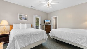 Una camera d'albergo con due letti, una ventola a soffitto, una televisione e un quadro appeso al muro.