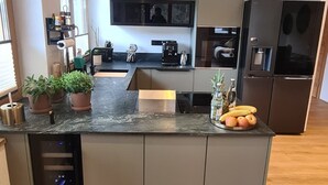 Une cuisine moderne dotée d’un îlot central intégré, d’une machine à café et d’un réfrigérateur.