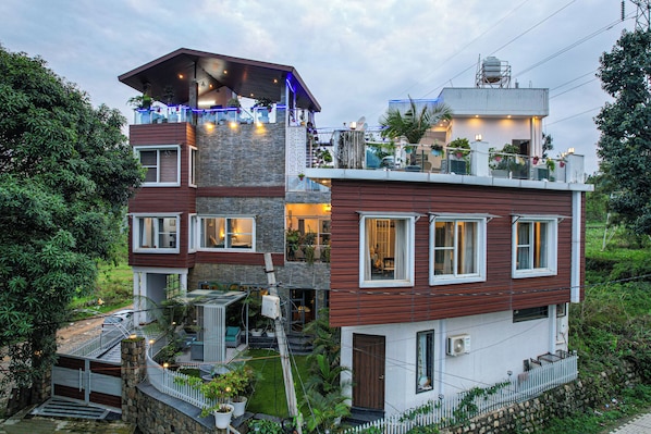 Een meerlaags huis met een balkon, een garage en een kleine tuin.