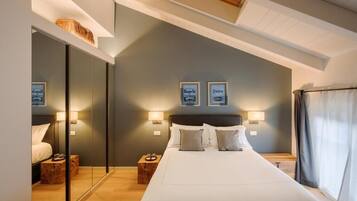 Una habitación de hotel moderna con una cama grande, mesitas de noche, un espejo y cuadros en la pared.