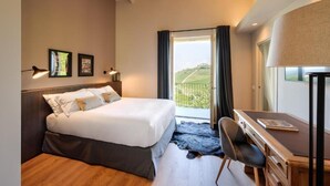 Ein Schlafzimmer mit Bett, Schreibtisch, Stuhl und Blick ins Freie.