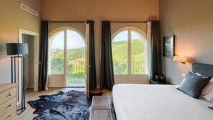 Ein Schlafzimmer mit einem Bett, einem Nachttisch, einer Lampe, einer Kommode, einem Teppich und zwei Fenstern mit Vorhängen.