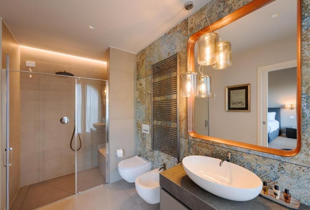 A modern bathroom with a glass-enclosed shower, a freestanding toilet, and a large oval sink with a mirror above it.