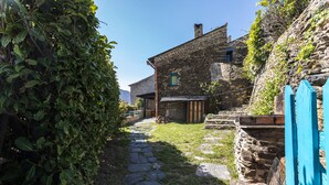Un bâtiment en pierre avec un étroit sentier également en pierre menant à une porte en bois.