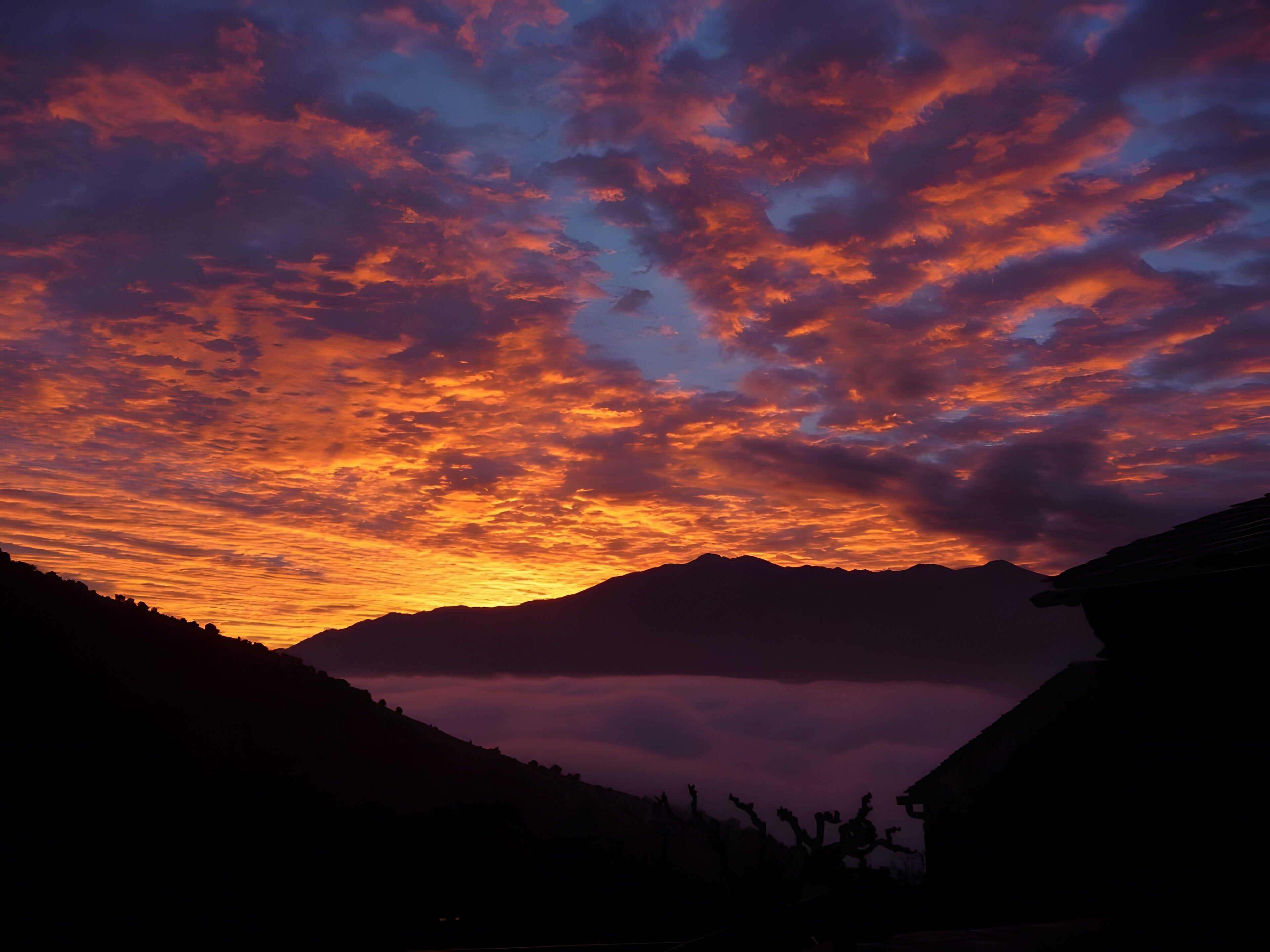Un atardecer con nubes vibrantes sobre montañas.