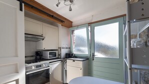 Een praktische keuken met een magnetron, fornuis, oven en een klein kastje.