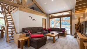 A spacious living area with a wooden staircase, a large window with a view, and a wall with motivational text. - Chalet in Paradiski With Spa & Stunning Views (Peisey-Nancroix)