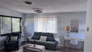 Un salon moderne avec un canapé gris, une table basse, une table d’appoint et une lampe.