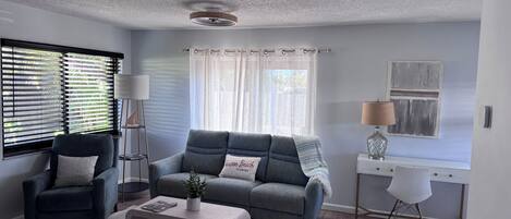 A modern living room with a grey sofa, a coffee table, a side table, and a lamp.
