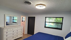 Une chambre à coucher avec un lit, une commode et une fenêtre donnant sur un beau paysage.