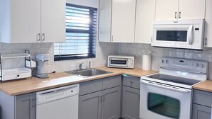 Une cuisine moderne avec des meubles blancs, un four à micro-ondes encastré, un grille-pain, un lave-vaisselle et un four.