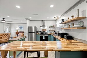 A modern kitchen with a central island, built-in appliances, and wooden shelves. - Beach House - Blueberry Beach (Panama City Beach)