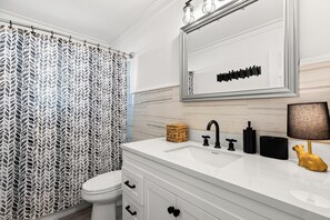 A bathroom with a white vanity, a mirror, a toilet, and a shower curtain. - Beach House - Blueberry Beach (Panama City Beach)