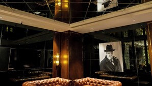 A modern lobby with a large, plush seating area, a unique geometric chandelier, and a large portrait on the wall. - HOTEL AVINASH INTERNATIONAL (Jagdalpur)