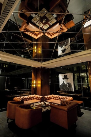 Eine moderne Lobby mit einem großzügigen, bequemen Sitzbereich, einem einzigartigen geometrischen Kronleuchter und einem großen Gemälde an der Wand.