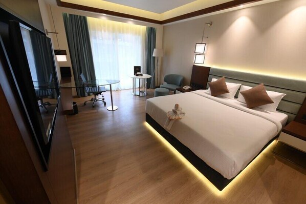 Habitación de hotel con una cama grande, mesitas de noche, un escritorio, una silla y un televisor.