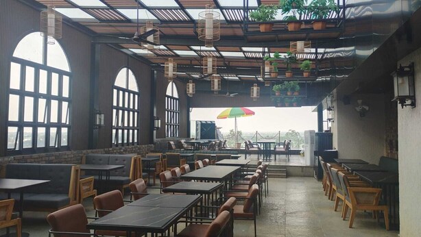 A restaurant with high ceilings, large windows, and multiple tables and chairs. - HOTEL AVINASH INTERNATIONAL (Jagdalpur)