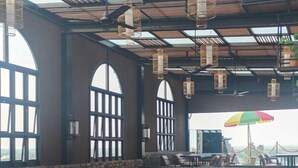 A spacious indoor dining area with high ceilings, large windows, and multiple tables and chairs. - HOTEL AVINASH INTERNATIONAL (Jagdalpur)
