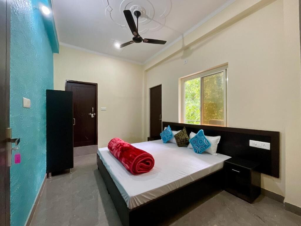 Una habitación de hotel con una cama, ventilador de techo, ventana y puerta.