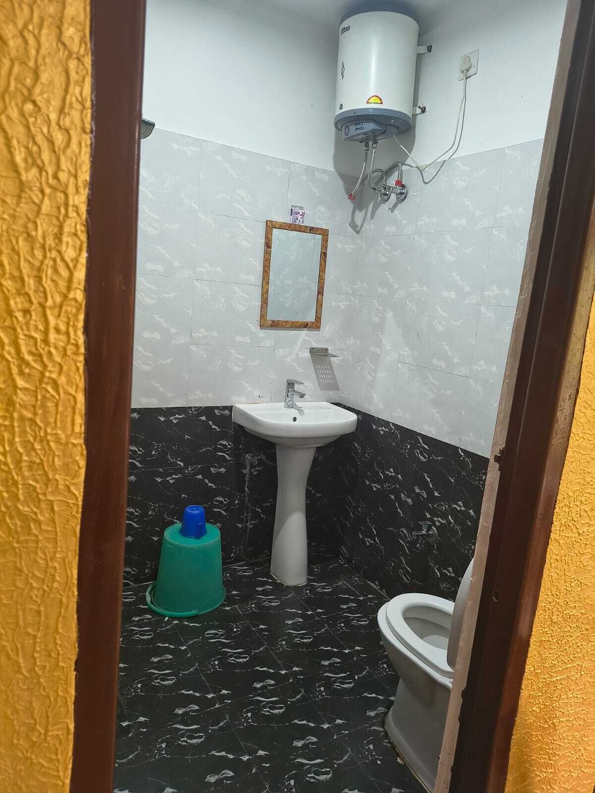 A bathroom with a white sink, a toilet, a mirror, and a water heater mounted on the wall.