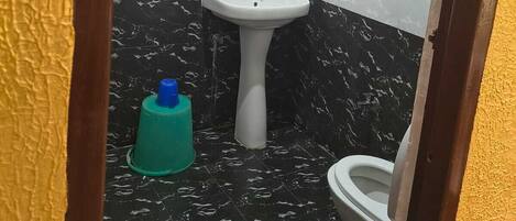A bathroom with a white sink, a toilet, a mirror, and a water heater mounted on the wall.