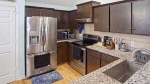 A kitchen with stainless steel appliances, dark wooden cabinets, granite countertops, and a built-in oven. - 3br Savannah Home Sleeps 5 Near Historic District 3 Bedroom Home (Savannah)