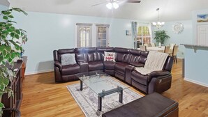 A living room with a leather sectional sofa, glass coffee table, and a ceiling fan. - 3br Savannah Home Sleeps 5 Near Historic District 3 Bedroom Home (Savannah)