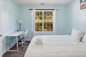 Un dormitorio con una cama, un escritorio y una ventana.