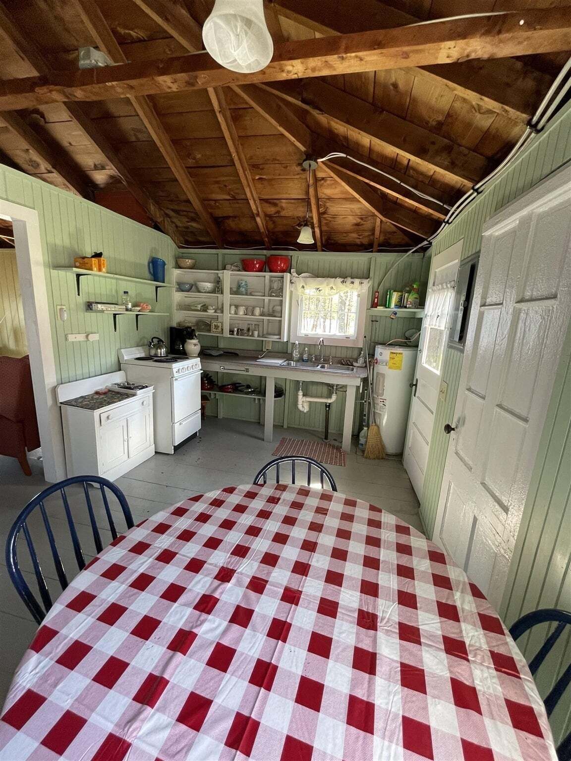 Une cuisine rustique avec des poutres en bois, une table à carreaux et des équipements de base.