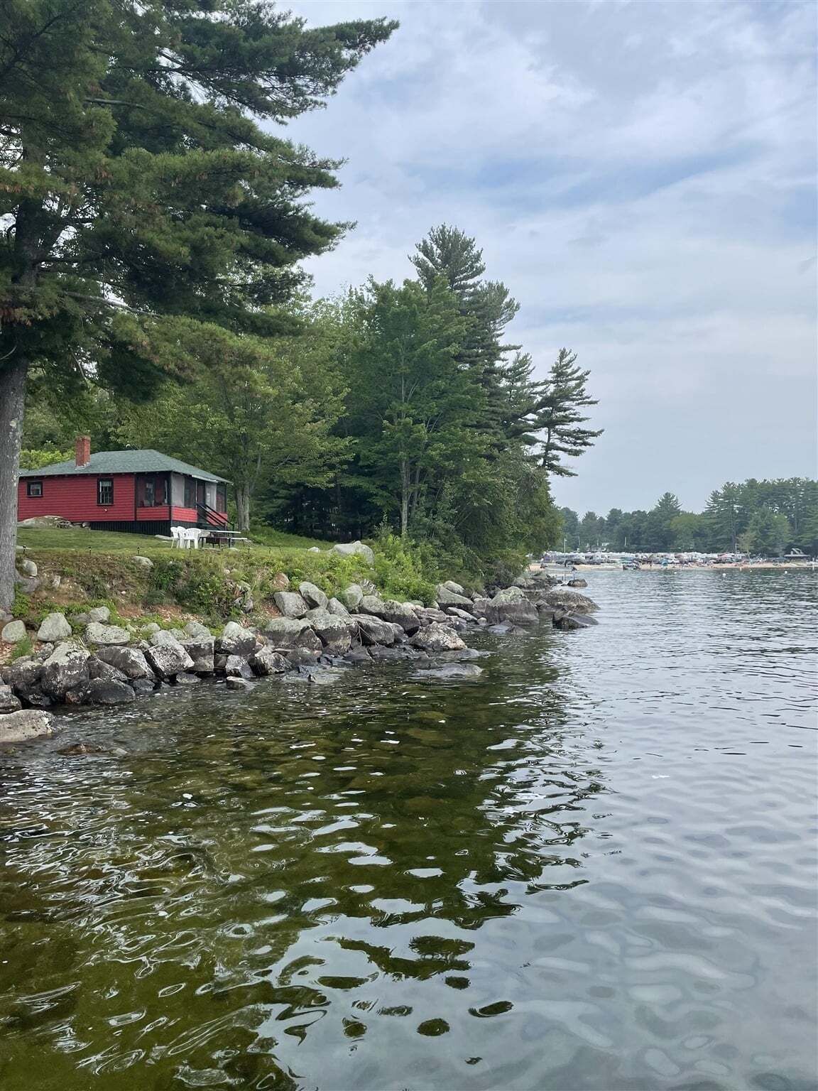 Un chalet au bord du lac, doté d’un quai, entouré d’arbres et bordé d’une rive rocheuse.