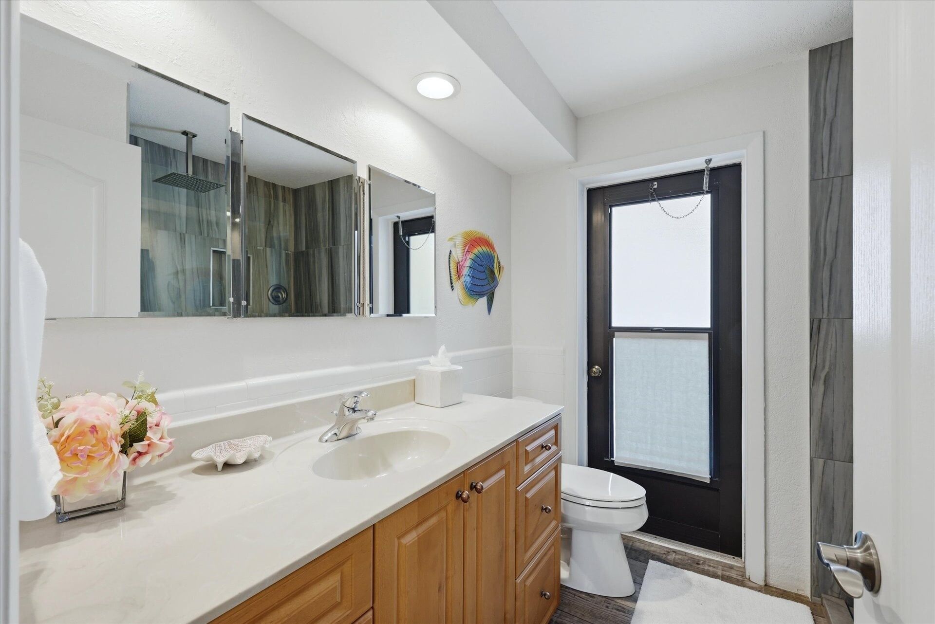 A bathroom with a white sink, wooden cabinets, a mirror, and a toilet.