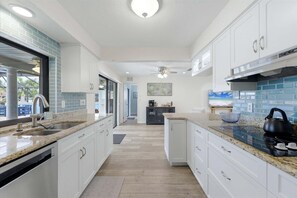 A modern kitchen with white cabinets, granite countertops, and a black kettle. - Doc301 3 Bedroom Home (Punta Gorda)