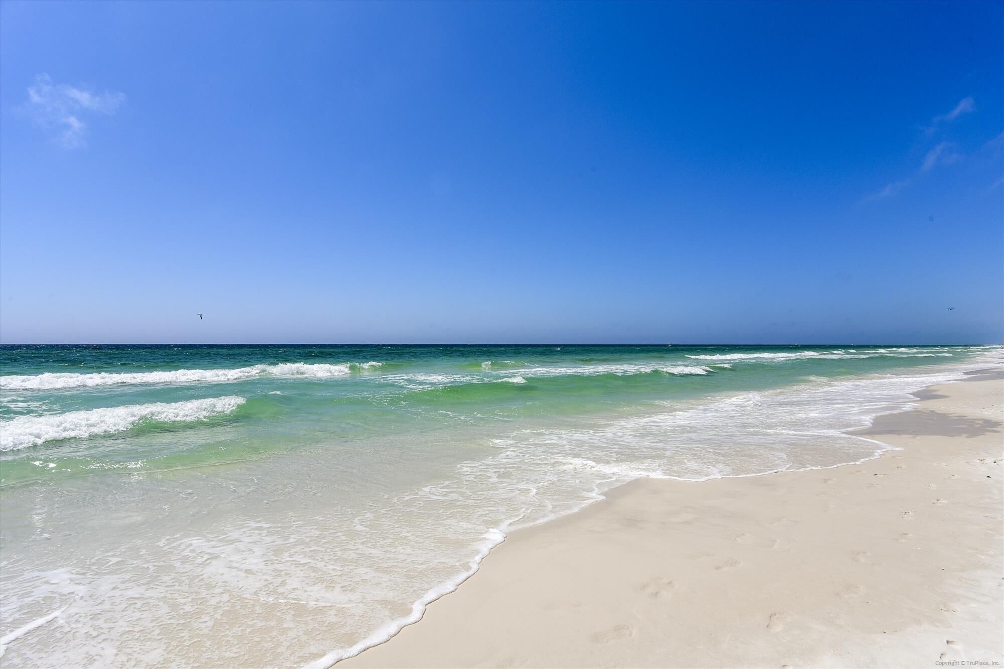 A beach with clear blue water and a sandy shore.