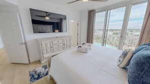 A hotel room with a bed, a dresser, a ceiling fan, a large window with a city view, and a balcony. - Silver Beach 0704e 3 Bedroom Condo (Destin)