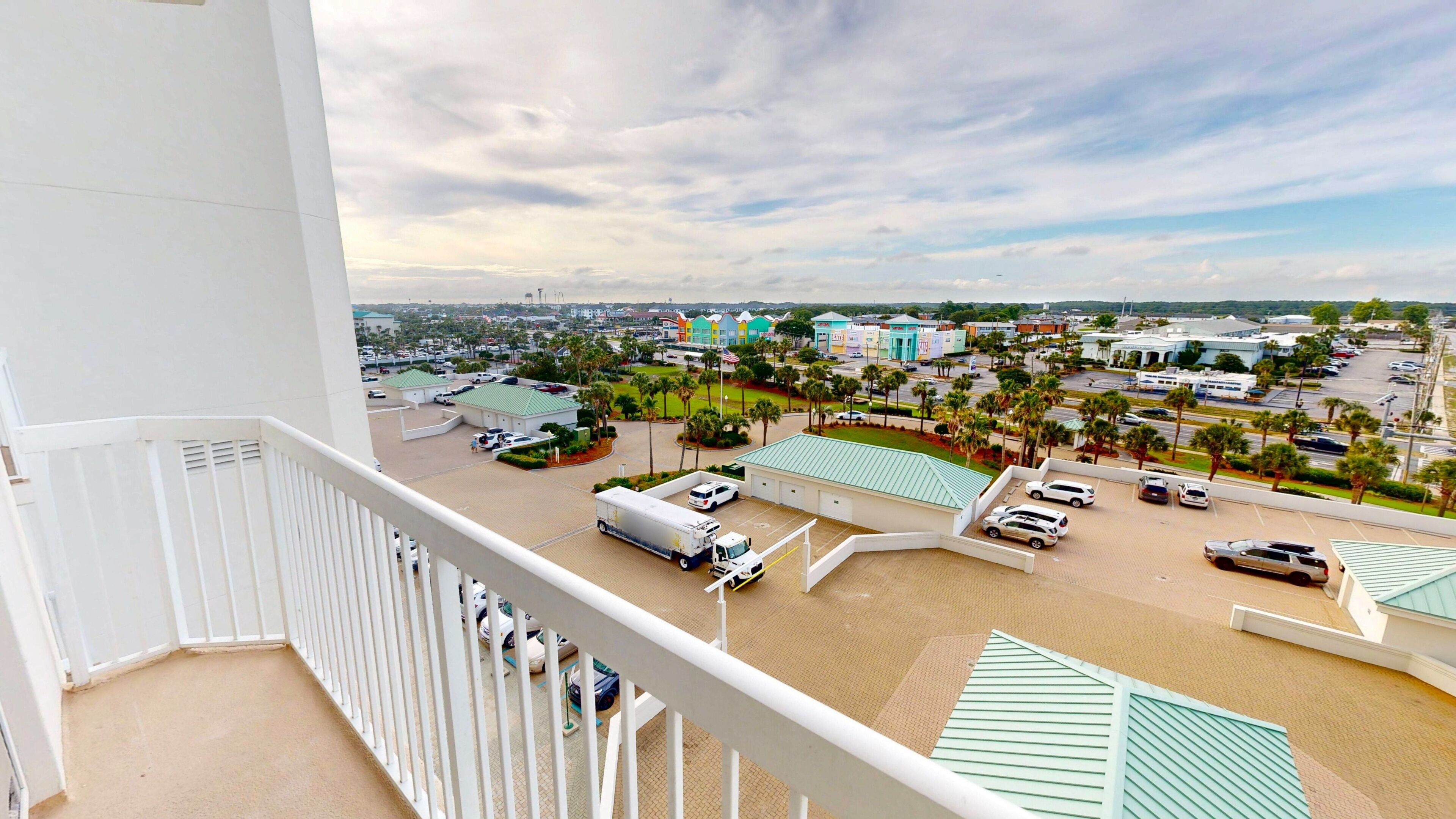 A high-rise hotel with a view of a parking lot, a green-roofed building, and a distant cityscape.