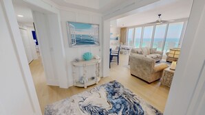 A spacious living area with a large window, a sofa, a dining table, and a decorative rug. - Silver Beach 0704e 3 Bedroom Condo (Destin)