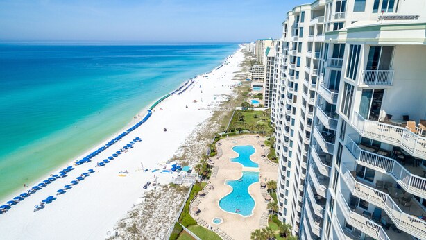 A beachfront hotel with a pool, beach umbrellas, and a view of the ocean. - Silver Beach 0704e 3 Bedroom Condo (Destin)