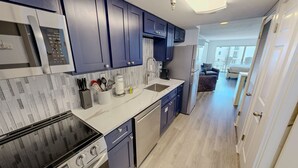 A modern kitchen with stainless steel appliances, blue cabinets, and a marble countertop. - Islander Beach Resort 407 1 Bedroom Condo (Fort Walton Beach)