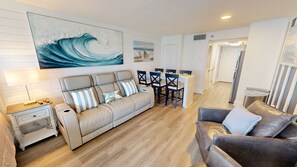 A living room with a sofa, a coffee table, and a dining area with chairs and a table. - Islander Beach Resort 407 1 Bedroom Condo (Fort Walton Beach)