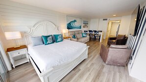 A bedroom with a large bed, a sofa, a dining table, and a TV. - Islander Beach Resort 407 1 Bedroom Condo (Fort Walton Beach)