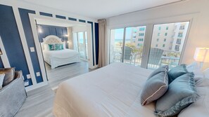 A hotel room with a large bed, a view of the cityscape, and a balcony with outdoor furniture. - Islander Beach Resort 407 1 Bedroom Condo (Fort Walton Beach)